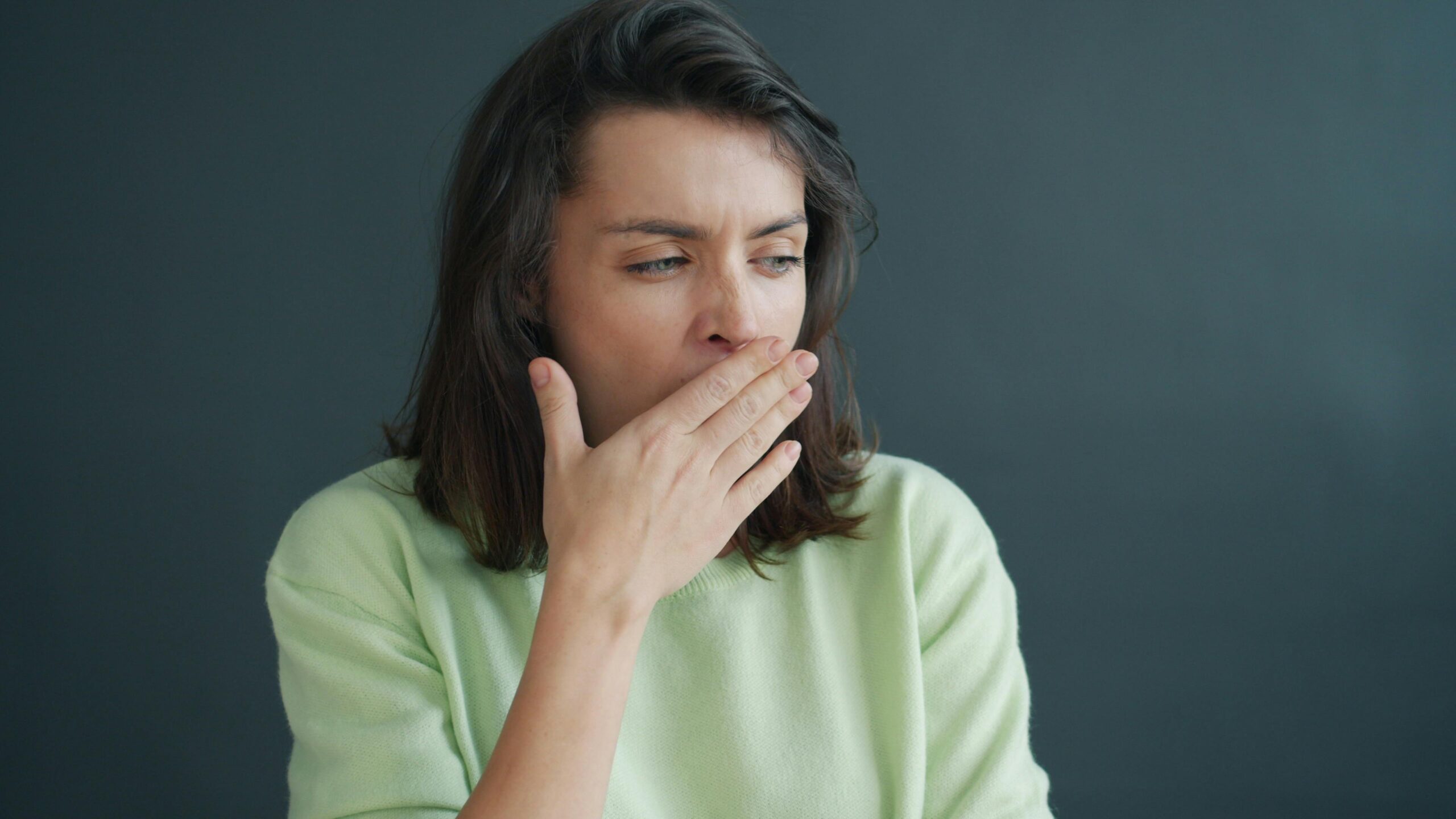 A woman checking if she has bad breath with her hand over her mouth